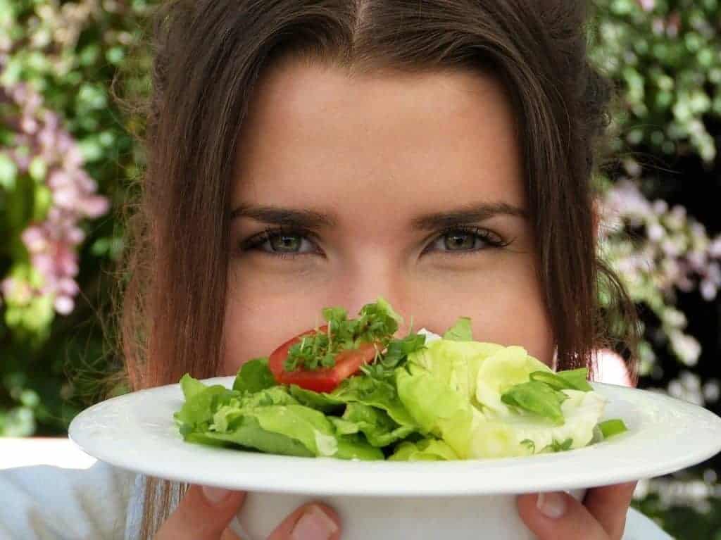 la mujer está sosteniendo un plato de ensalada