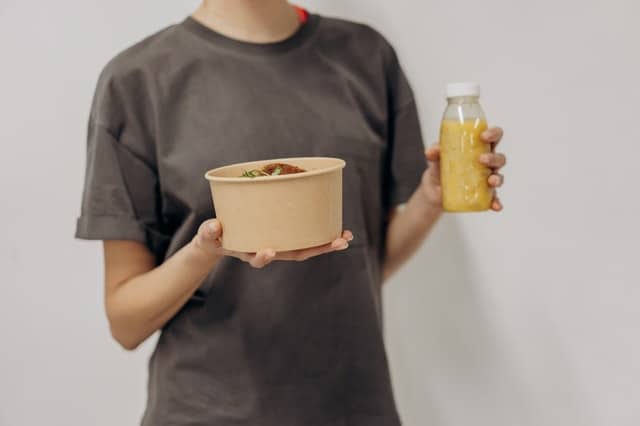 una mujer sostiene un bol de comida y un batido