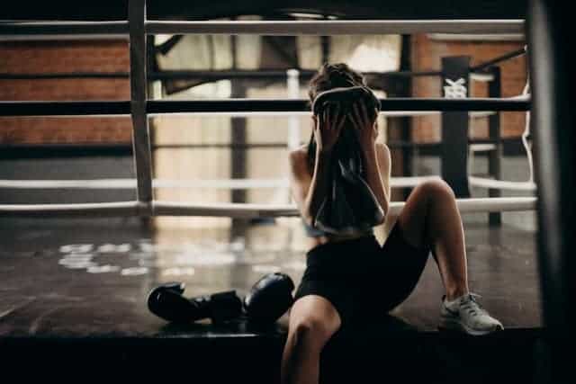 una mujer se limpia el sudor de la cara después de un entrenamiento extenuante