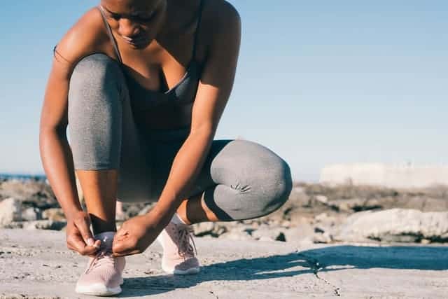 mujer en ropa deportiva se ata el zapato