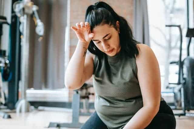  mujer con sobrepeso cansada después de un entrenamiento