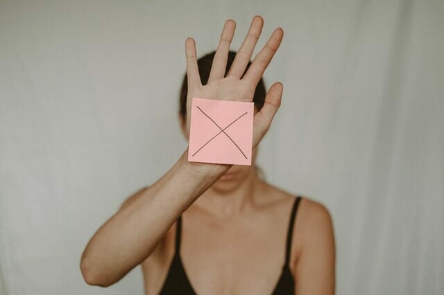 una mujer triste sostiene una caja de cartón con una x delante