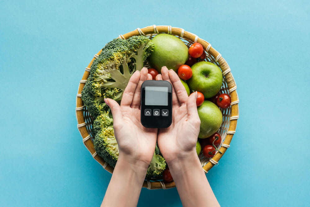  Un bol con verduras y frutas, junto a un medidor de glucosa manual
