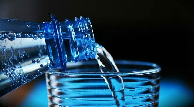 Agua vertida de una botella a un vaso