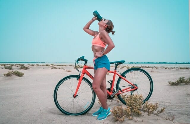 una mujer bebe agua de una botella después de un paseo en bicicleta