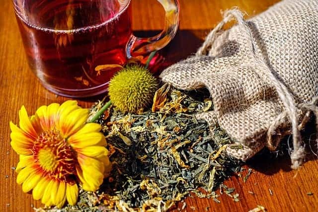  Infusión de hierbas en un vaso, junto a las hierbas a granel