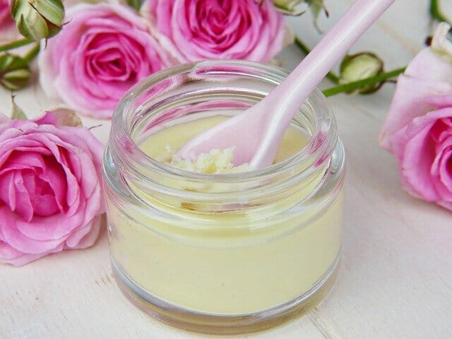  Un bote de crema facial casera, junto a las rosas