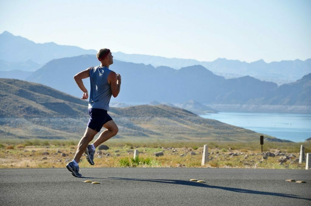 hombre corriendo, montañas y lago de fondo
