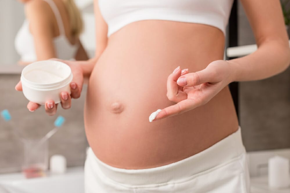 embarazada lubrica su vientre con crema