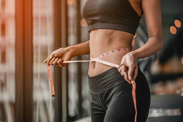  una mujer se mide la cintura con una cinta métrica