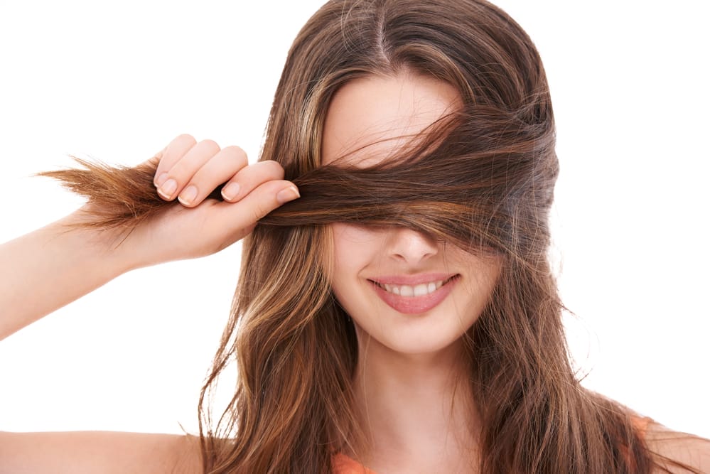una mujer sostiene su cabello grueso y fuerte en la mano